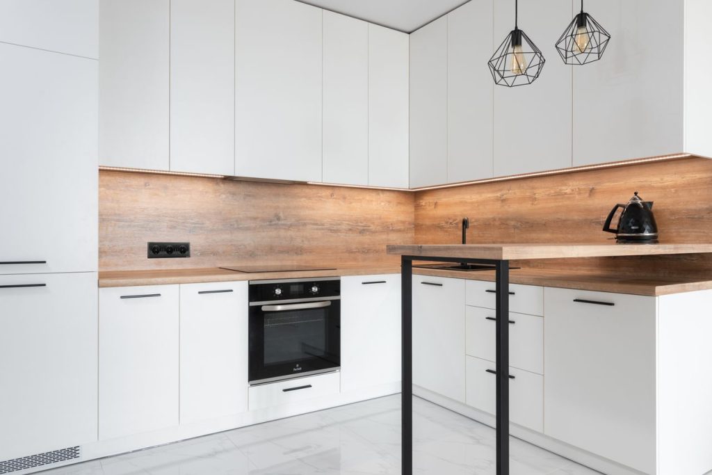 Modern kitchen with contemporary interior with metal geometrical lamps and new white cabinets