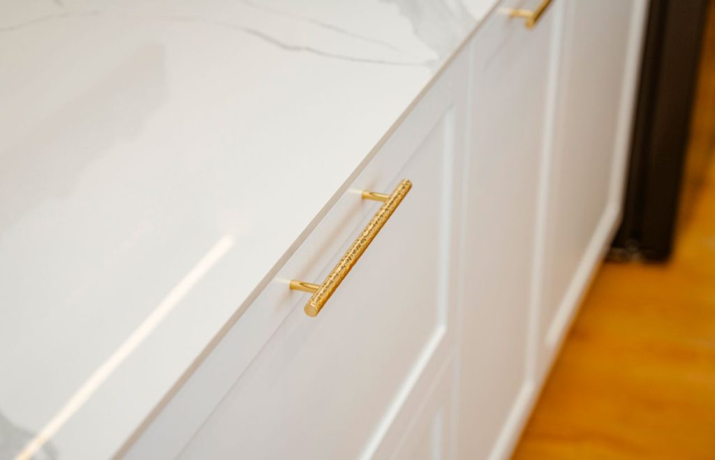 Sophisticated white cabinet with gold handles and marble top, perfect for modern interiors.