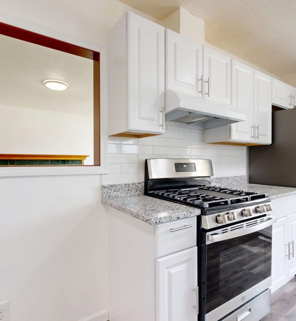 Bright white kitchen featuring stainless steel stove and fridge with granite countertops.